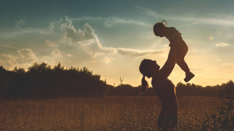 Silhouette of a young mother and her little daughter at sunset