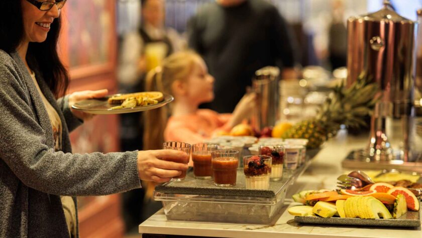 Guests enjoy a vibrant breakfast buffet with fresh fruits, pastries, and juices, set in a welcoming hotel dining area.