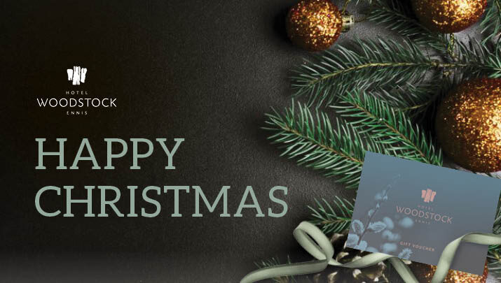 Festive decorations with gold baubles, green pine branches, and Hotel Woodstock gift voucher evoke holiday warmth.