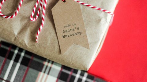 A gift wrapped in brown paper with red and white string, featuring a tag that reads