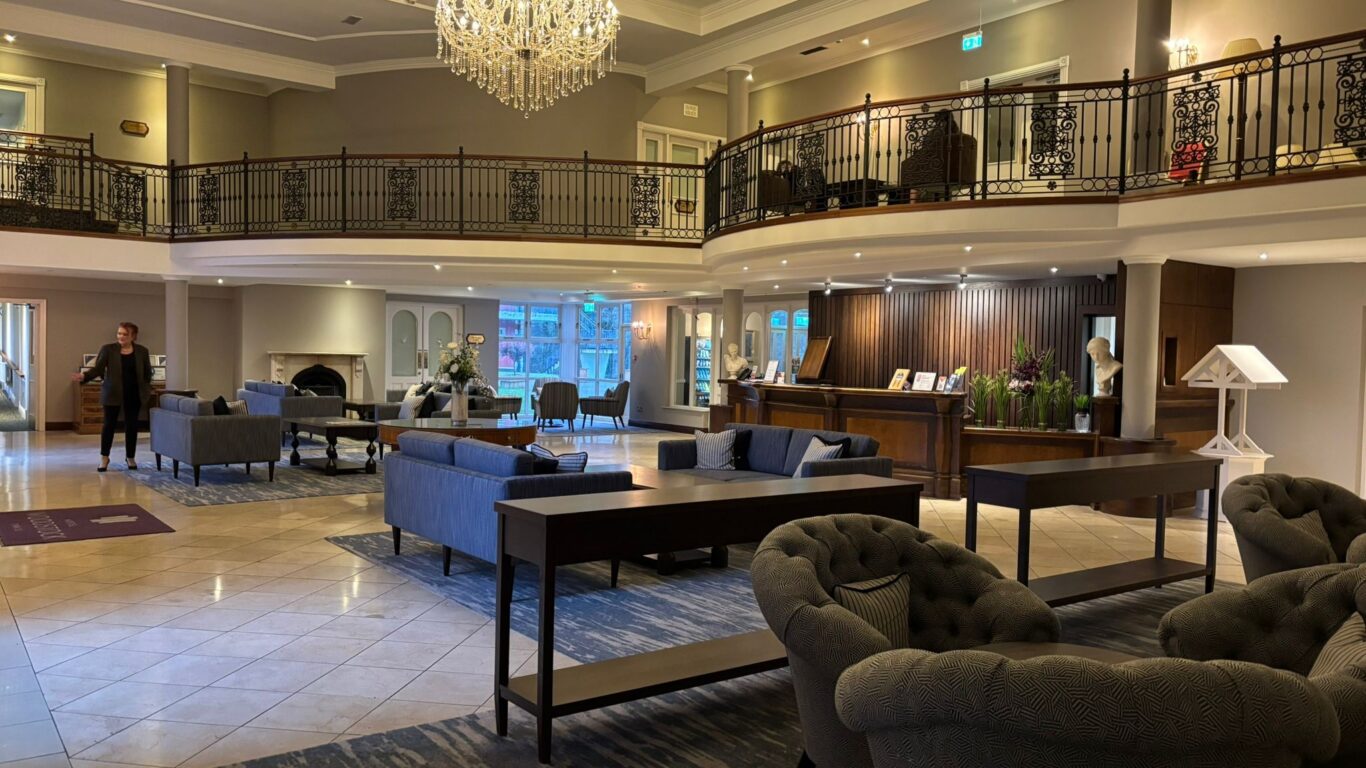 Elegant hotel lobby with grand chandelier, cosy seating, and welcoming reception desk for a luxurious guest experience.