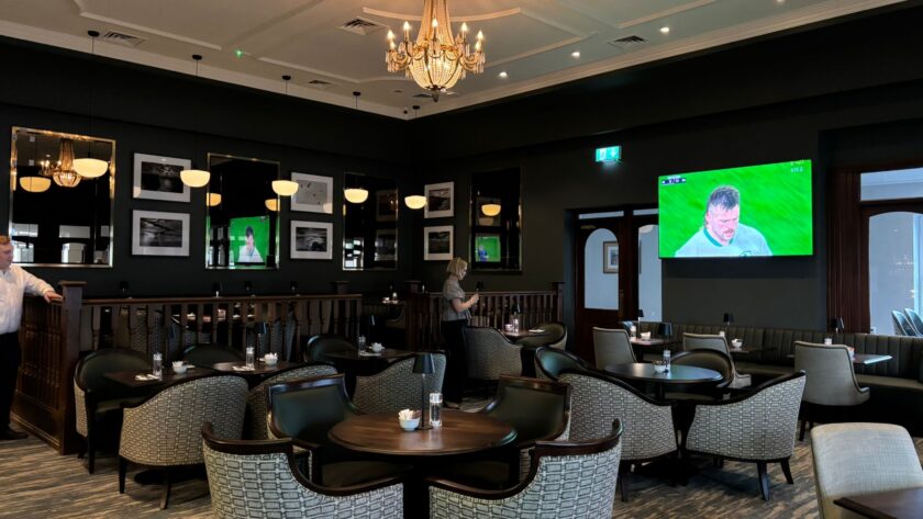 Elegant hotel lounge with comfy seating, framed artworks, ambient lighting, and a large TV for relaxation and entertainment.