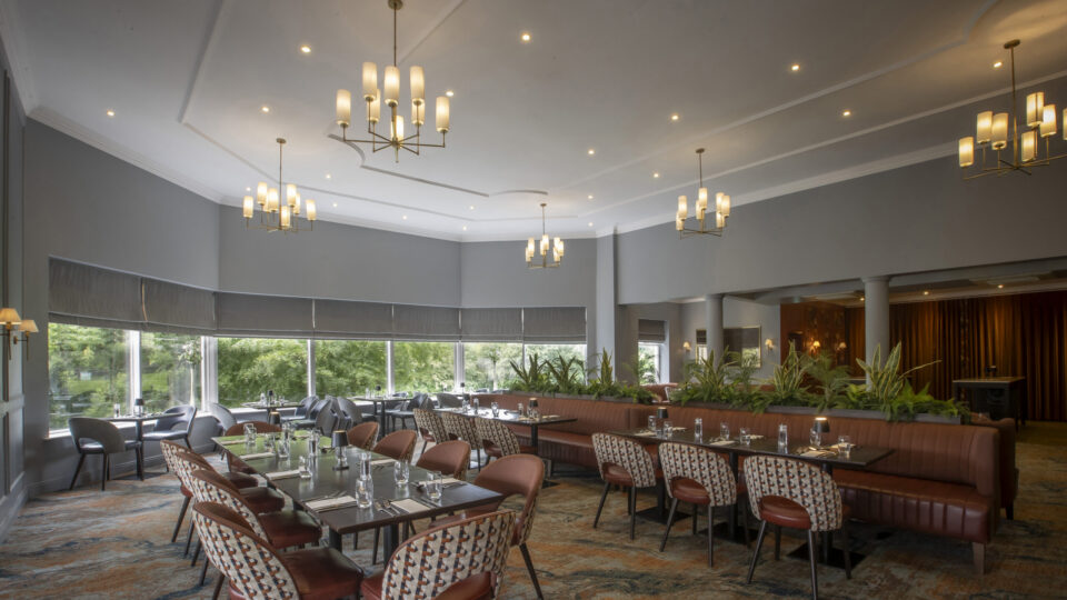 Spacious hotel dining room with modern d&eacute;cor, elegant lighting, large windows, and garden views. Perfect for relaxed meals.