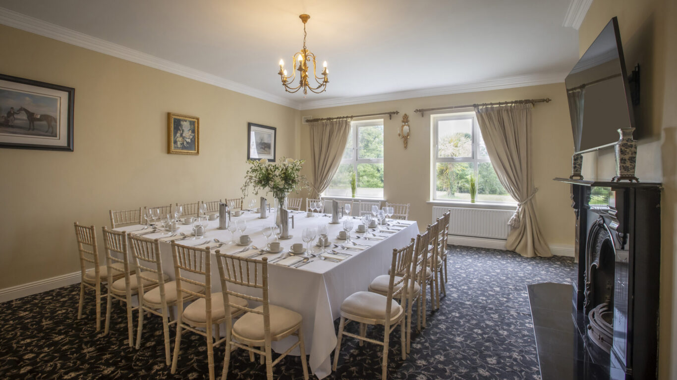 Intimate private dining room with U-shaped table, white linen, floral centrepiece, chandelier and garden-view windows &mdash; ideal for events.