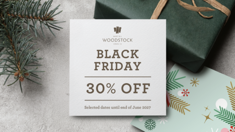Festive Black Friday 30% off card on textured table with fir sprig, wrapped gift and holiday card &mdash; cosy hotel offer, booking sale.