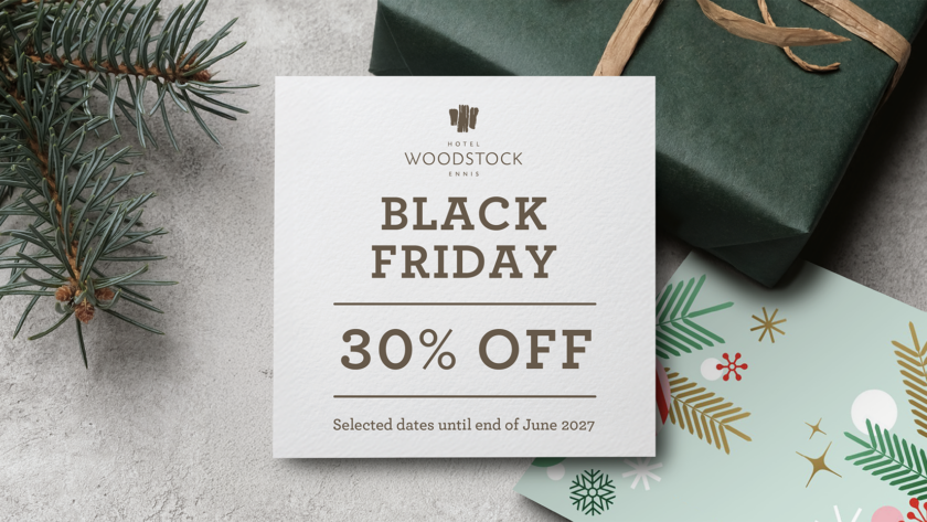 Festive Black Friday 30% off card on textured table with fir sprig, wrapped gift and holiday card &mdash; cosy hotel offer, booking sale.