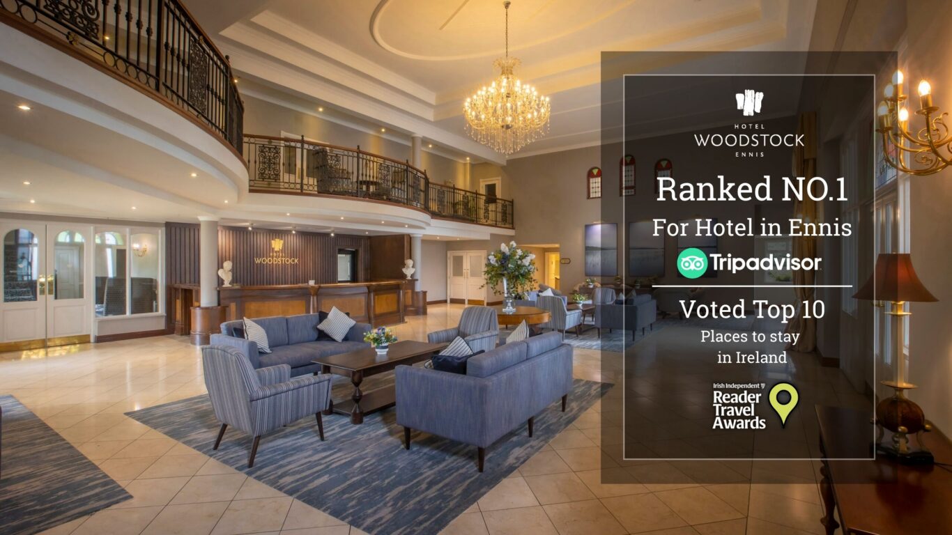Elegant hotel lobby with crystal chandelier, mezzanine balcony, reception desk and cosy blue sofas beside floral centrepieces &mdash; welcoming stay.